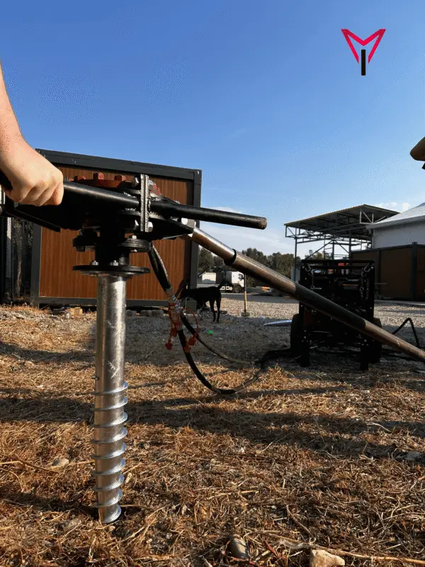 Helical pile machine beside a wooden cabin foundation