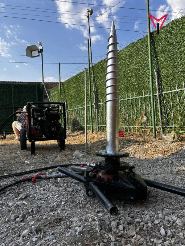 Screw pile machine positioned on green grass