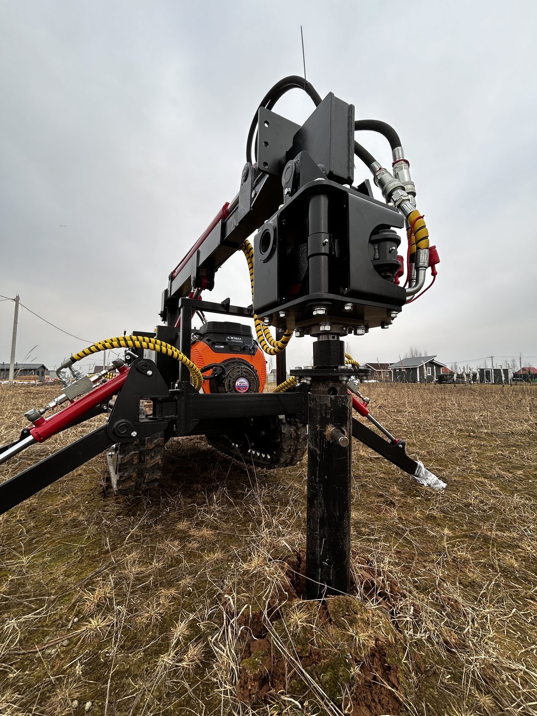 Tracked helical pile machine installing a screw pile